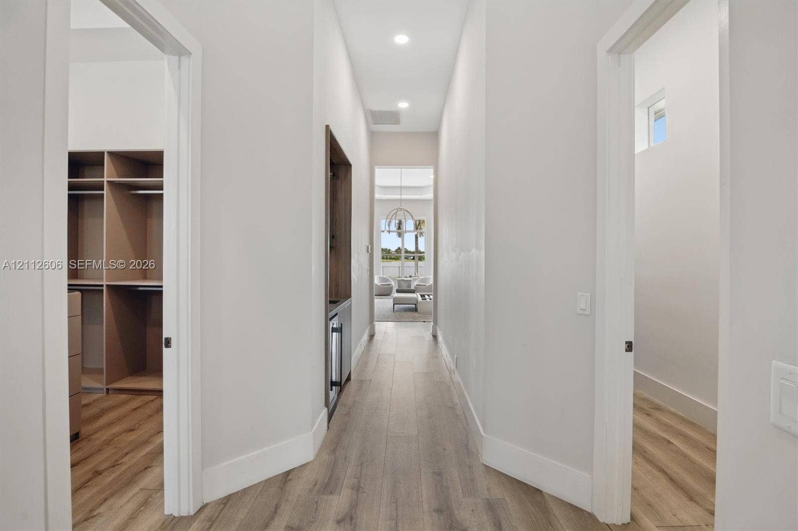 Hallway featuring wood-finish flooring, recessed lighting, built-in cabinetry with integrated beverage refrigeration, and custom-fitted closet shelving