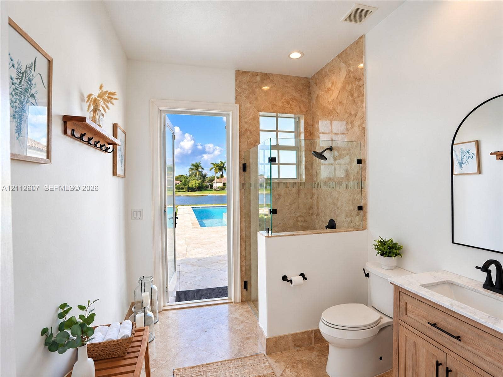 14443 S Jockey Circle S, Davie, FL 33330 Bathroom featuring a walk-in shower with stone tile surround, glass enclosure, and matte black fixtures, paired with a wood-finish vanity topped with a stone countertop