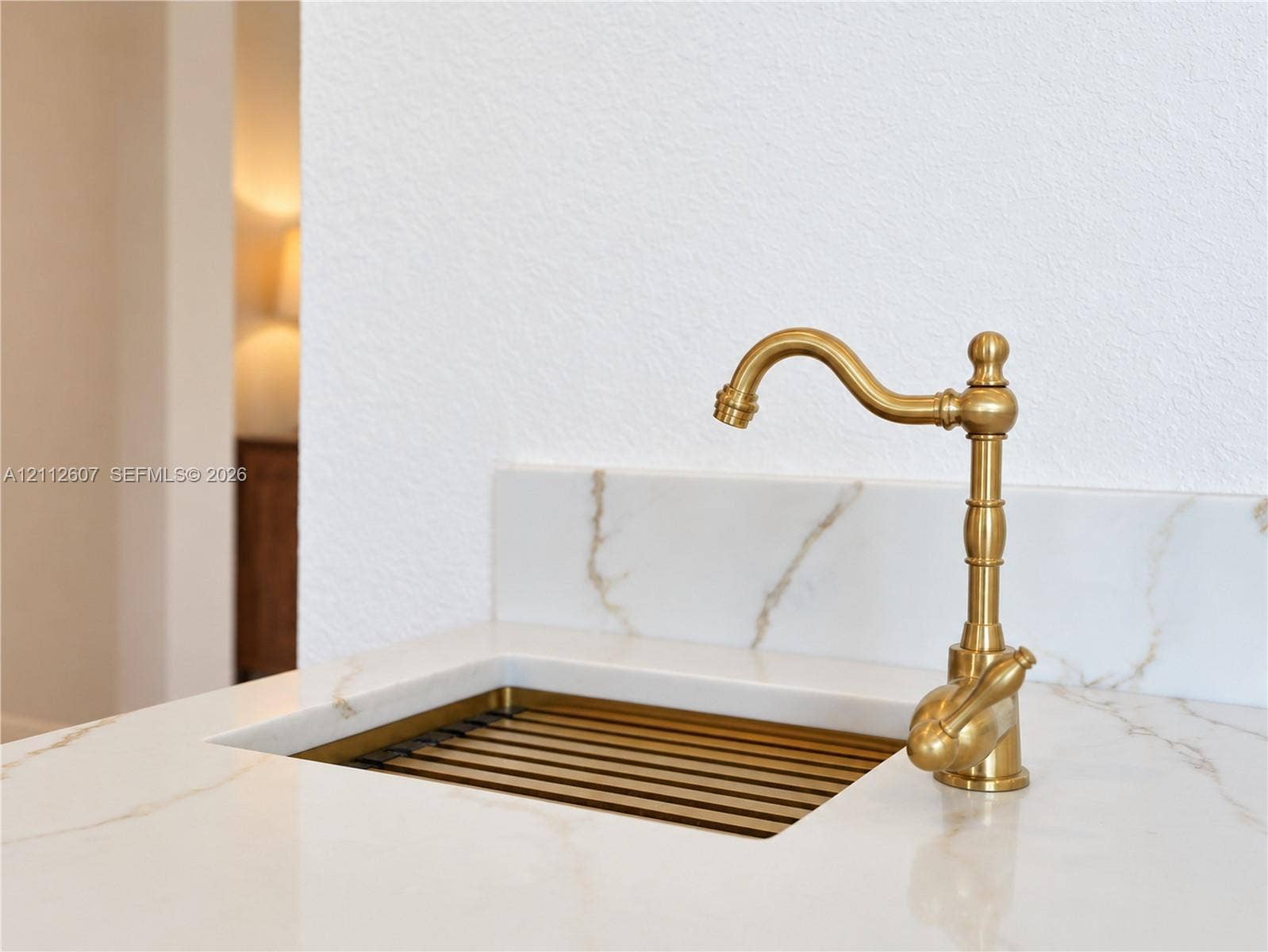 14443 S Jockey Circle S, Davie, FL 33330 Integrated stone-finish countertop with a coordinating backsplash, featuring a custom metal-finish sink basin and a decorative brass-finish gooseneck faucet
