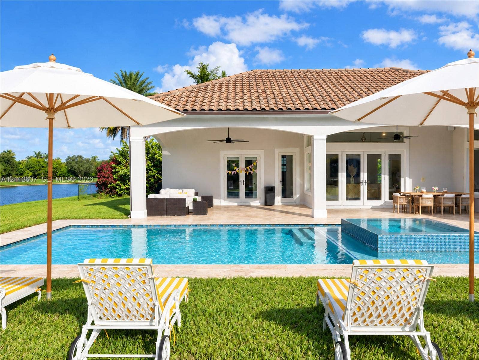 14443 S Jockey Circle S, Davie, FL 33330 Covered patio with a tile roof, rectangular swimming pool with an integrated spa, and limestone paver decking