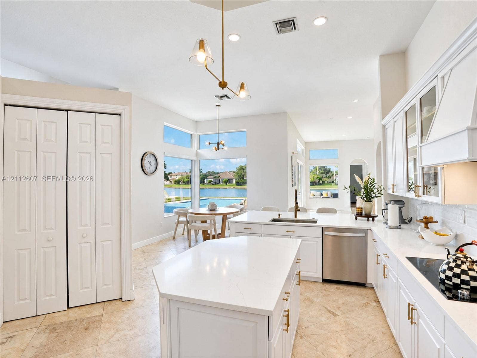 14443 S Jockey Circle S, Davie, FL 33330 Kitchen featuring white cabinetry, center island with stone-finish countertops, stainless steel appliances, tile flooring, and floor-to-ceiling windows