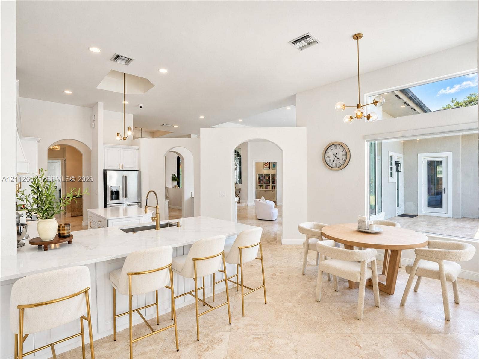 14443 S Jockey Circle S, Davie, FL 33330 Open-concept interior featuring high ceilings, stone flooring, a center island with stone countertop, brass-finish pendant lighting, and arched architectural openings