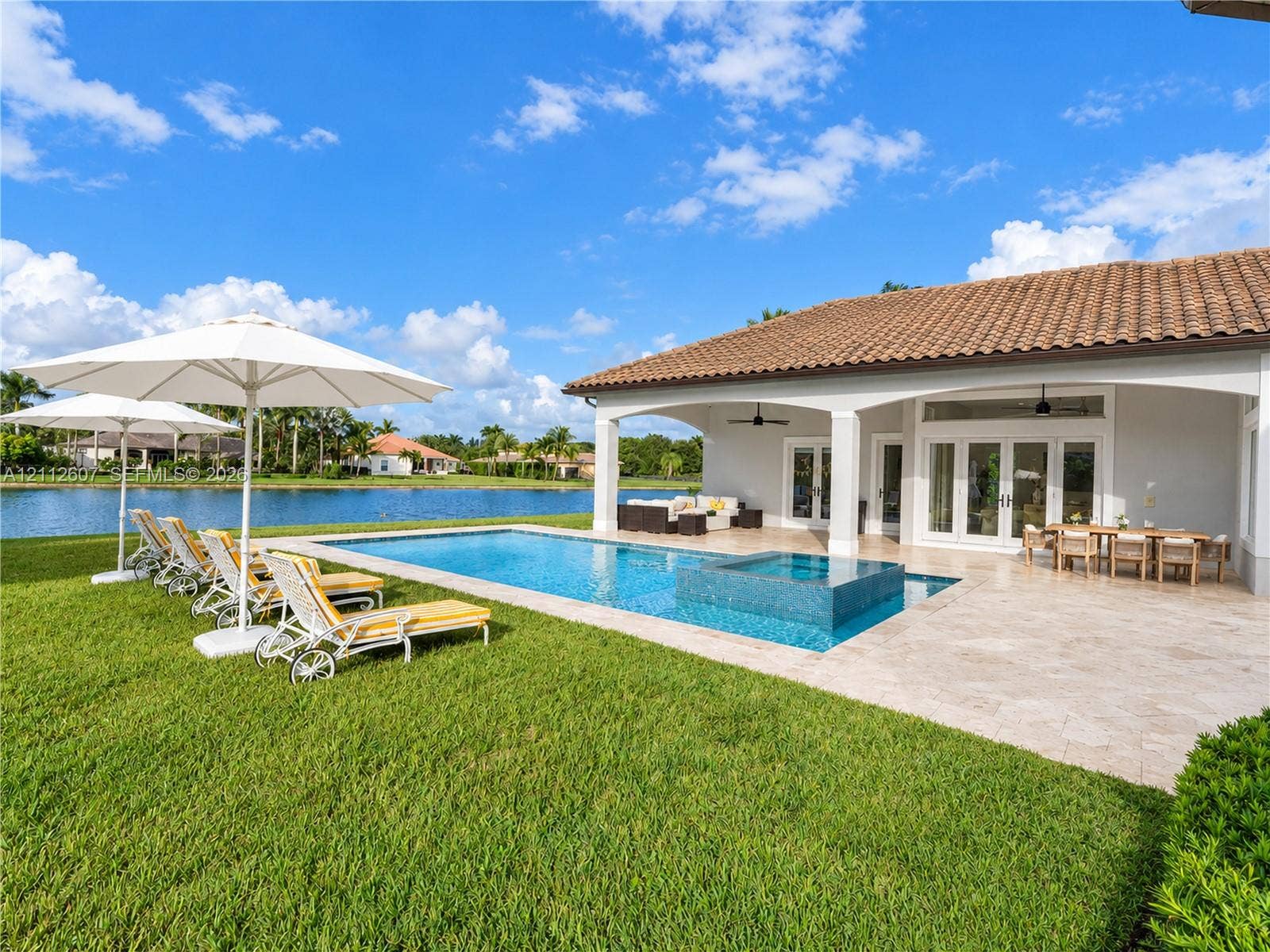14443 S Jockey Circle S, Davie, FL 33330 Covered patio with a tile roof, pool and integrated spa with stone tile surround, stone-paved deck, and water frontage