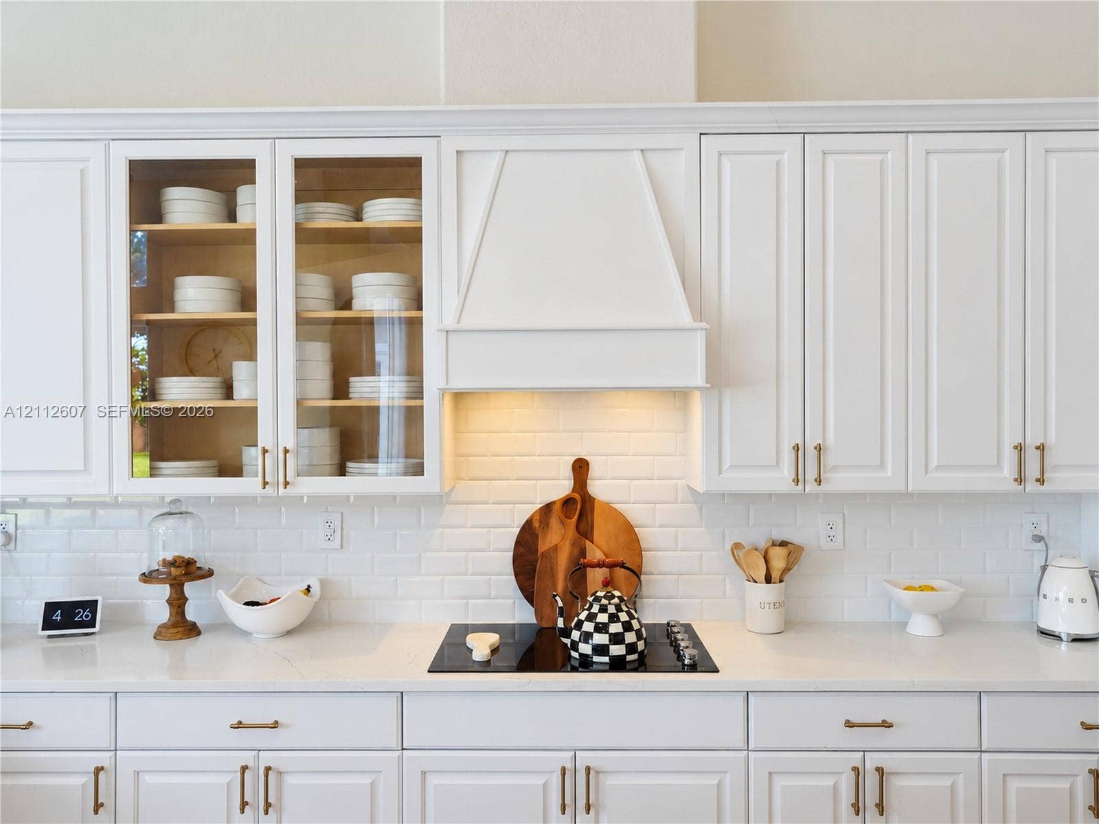 14443 S Jockey Circle S, Davie, FL 33330 Kitchen featuring white cabinetry with glass-front uppers, a custom range hood, subway tile backsplash, solid-surface countertops, and gold-tone hardware