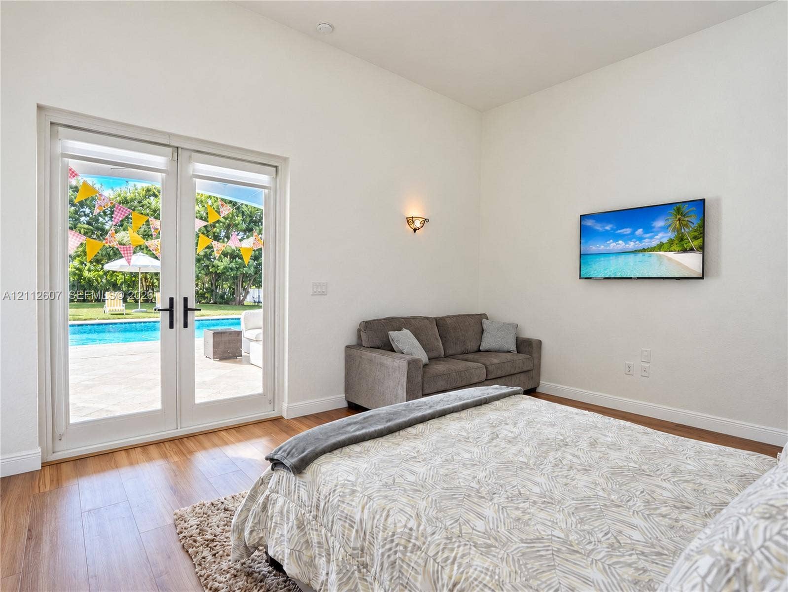 14443 S Jockey Circle S, Davie, FL 33330 Full-height glass French doors featuring matte black hardware, wood-finish flooring, and a wall-mounted light fixture