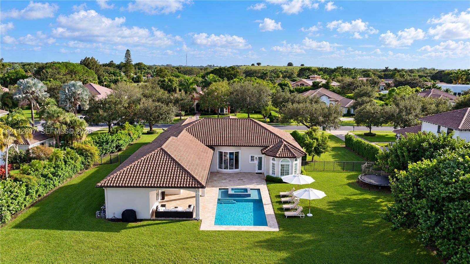 14443 S Jockey Circle S, Davie, FL 33330 Single-story residence featuring a tile roof, covered patio, integrated swimming pool with spa, and expansive lawn
