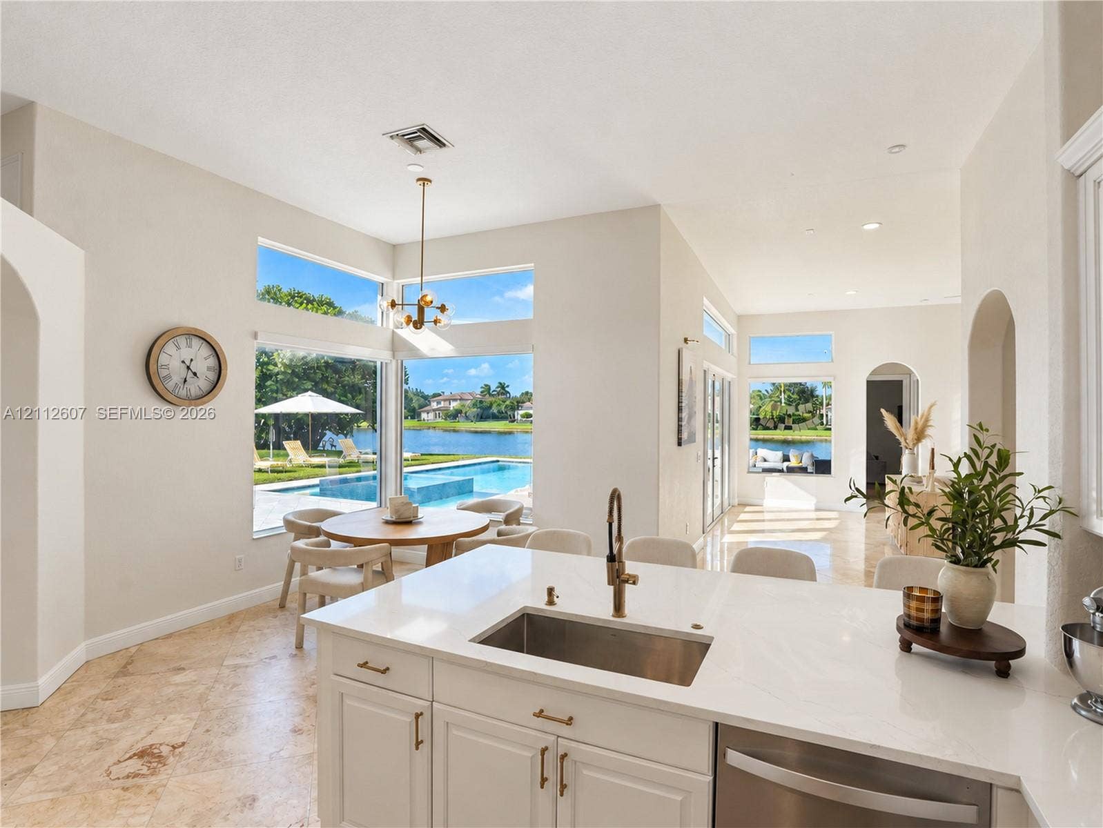 14443 S Jockey Circle S, Davie, FL 33330 Kitchen featuring stone flooring, white cabinetry, a quartz countertop, an undermount stainless steel sink with a metallic faucet, and expansive floor-to-ceiling windows