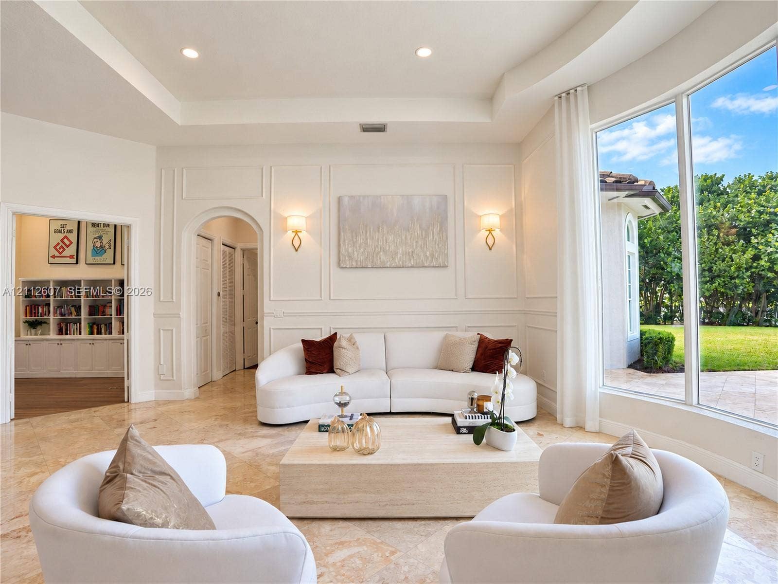 14443 S Jockey Circle S, Davie, FL 33330 Living area featuring tray ceilings, wainscoting, arched architectural details, polished stone flooring, and expansive floor-to-ceiling windows