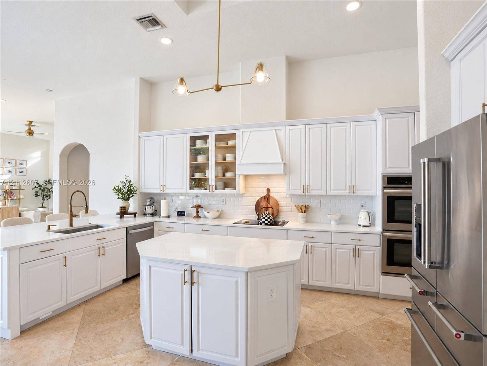 14443 S Jockey Circle S, Davie, FL 33330 Kitchen featuring white shaker-style cabinetry, central island with stone-finish countertops, stainless steel double wall ovens, brick-pattern backsplash, and stone tile flooring