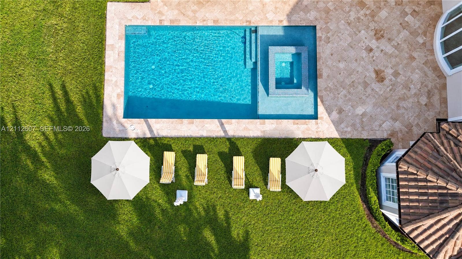 14443 S Jockey Circle S, Davie, FL 33330 Rectangular swimming pool featuring a spillover spa and stone-paver decking, set within a manicured lawn