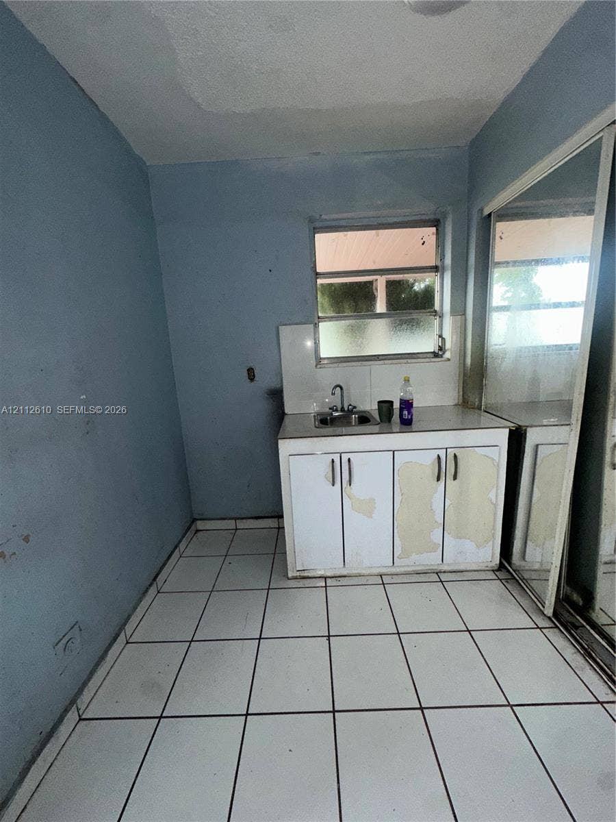 Hialeah, FL 33013 Built-in cabinetry with integrated sink, metal-framed window, and white ceramic tile flooring