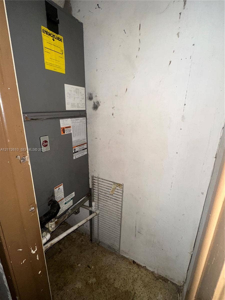Hialeah, FL 33013 Dedicated mechanical closet featuring a vertical HVAC unit with associated plumbing and a wire metal shelving rack