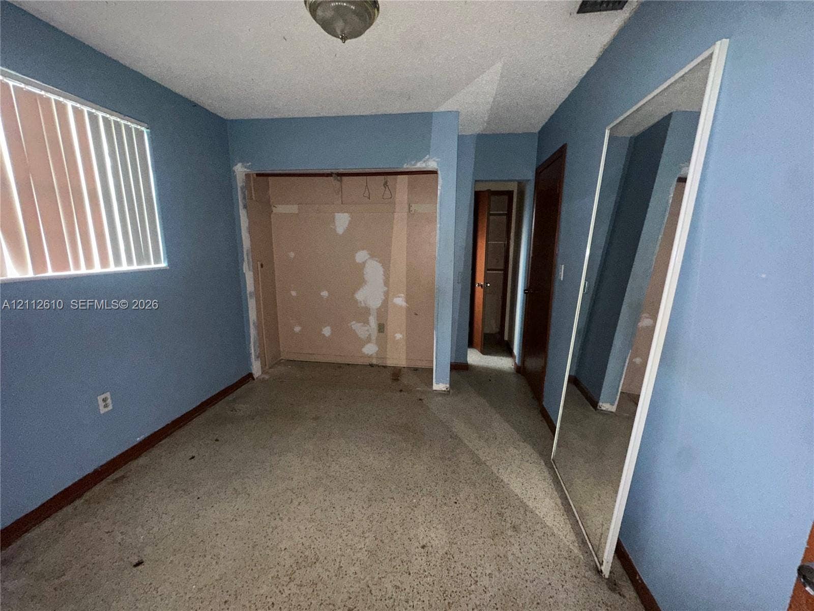 Hialeah, FL 33013 Room featuring speckled terrazzo flooring, vertical window blinds, and solid-core interior doors