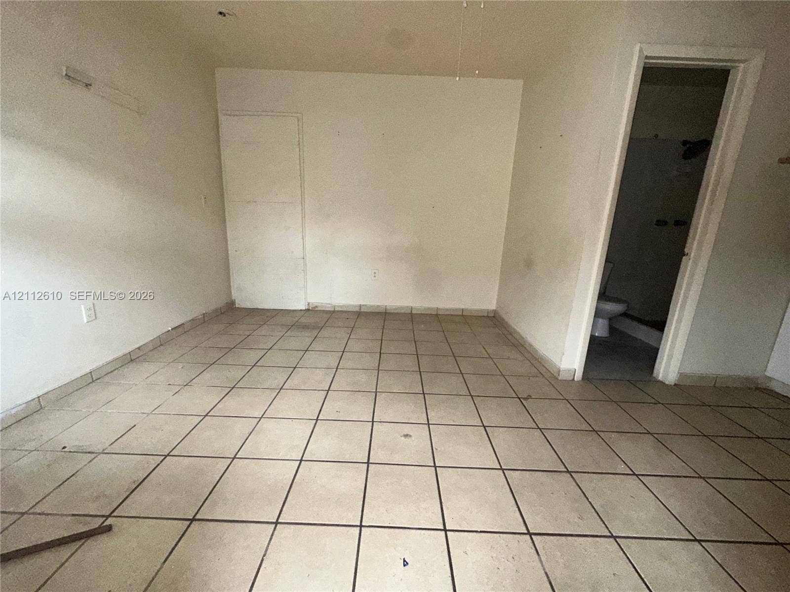 Hialeah, FL 33013 Interior room featuring light-toned ceramic tile flooring and a doorway leading to a tiled bath area