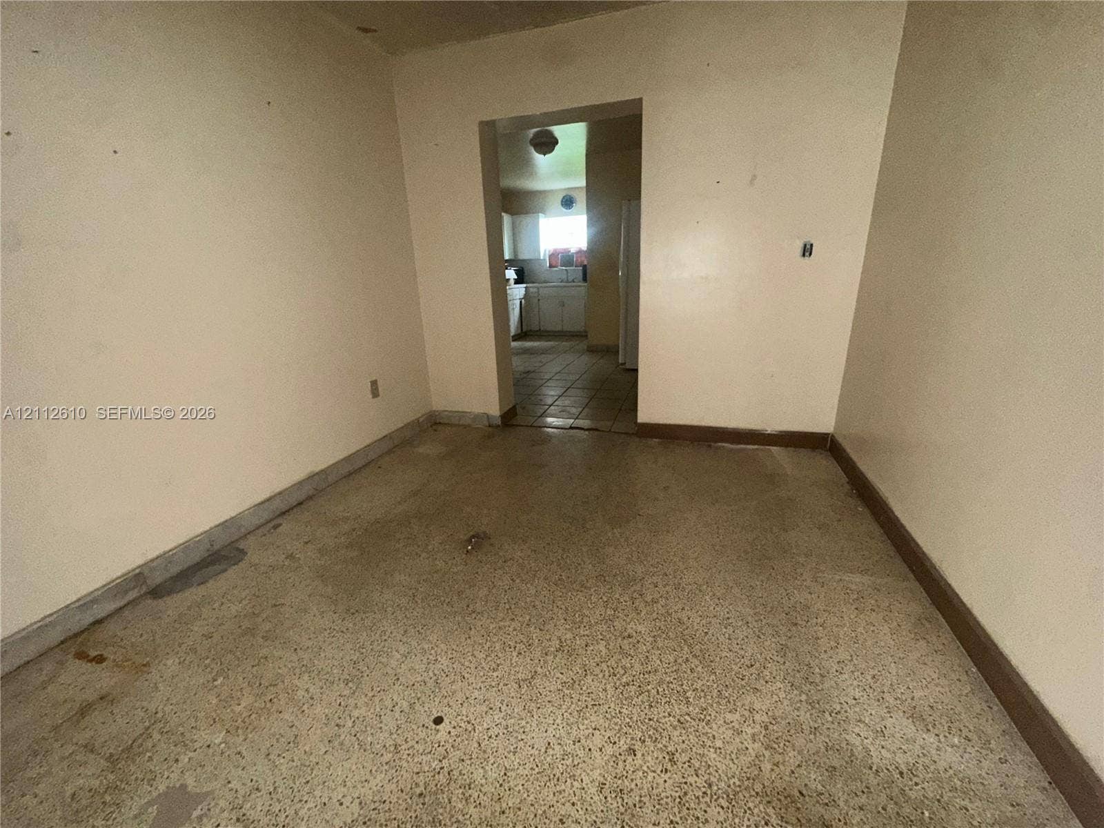 Hialeah, FL 33013 Interior space featuring terrazzo flooring and a threshold leading to a secondary room with tiled flooring and white cabinetry