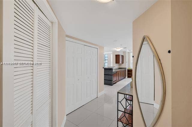 Interior area featuring high-gloss tile flooring, white bi-fold closet doors, and recessed ceiling lighting