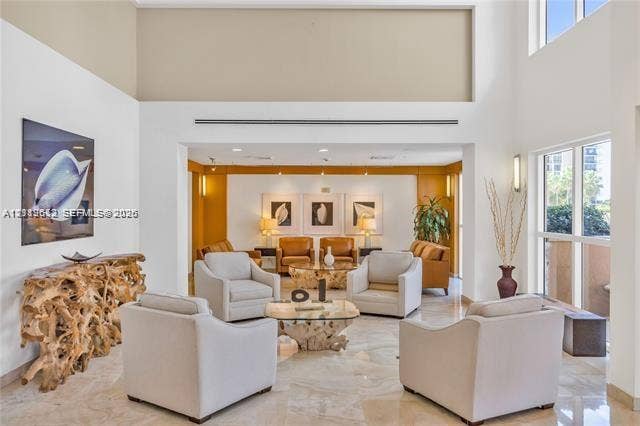 High-ceiling interior space featuring stone flooring, linear recessed lighting, and expansive floor-to-ceiling windows