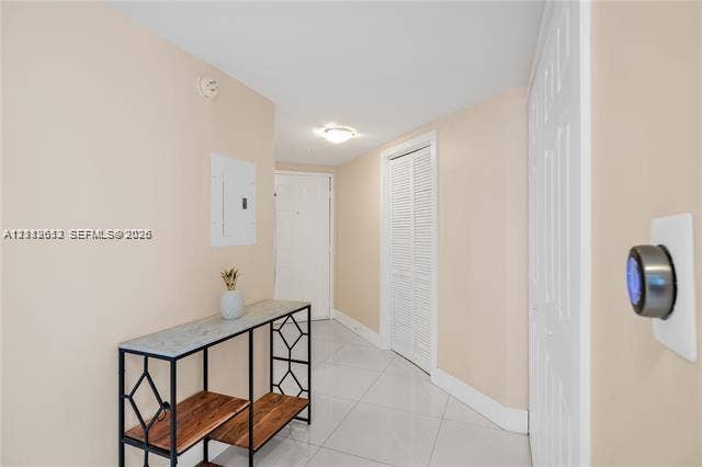 Interior hallway featuring light-toned flooring, white louvered closet doors, and a smart thermostat