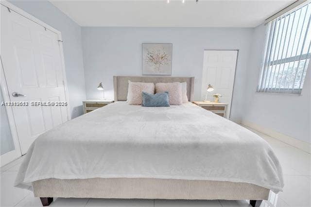 Bedroom featuring white tile flooring, vertical window blinds, and dual interior paneled doors