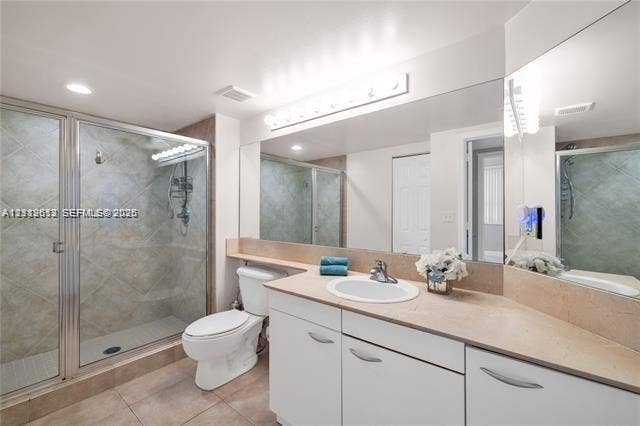 Full-width vanity with a neutral solid-surface countertop and recessed basin, glass-enclosed shower with tile surround, and expansive wall-to-wall mirror