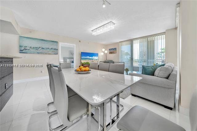 Open-concept living space featuring high-gloss tile flooring, floor-to-ceiling sliding glass doors, and a rectangular, modern tiered crystal ceiling fixture