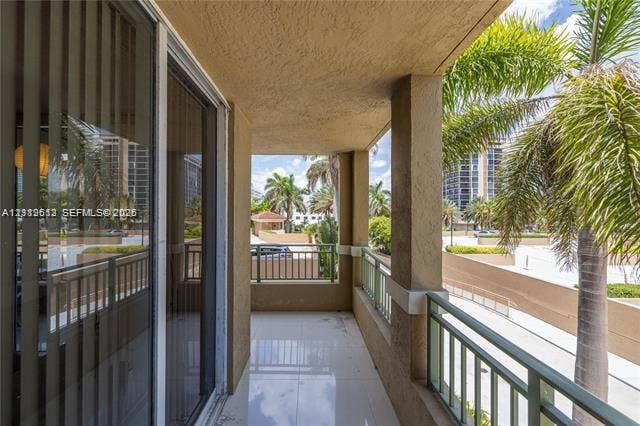 Covered balcony featuring tile flooring, metal railings, and a stucco ceiling