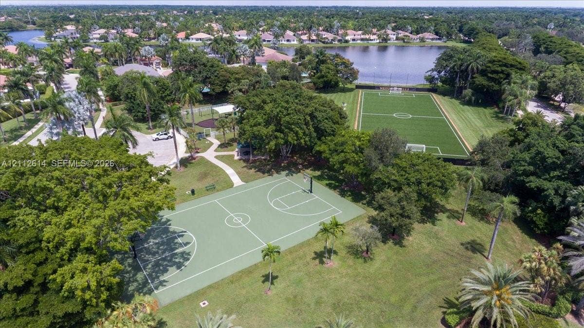 1422 Victoria Isle Drive, Weston, FL 33327 Recreational park featuring a full-size basketball court, synthetic turf soccer field, paved pathways, and mature canopy trees