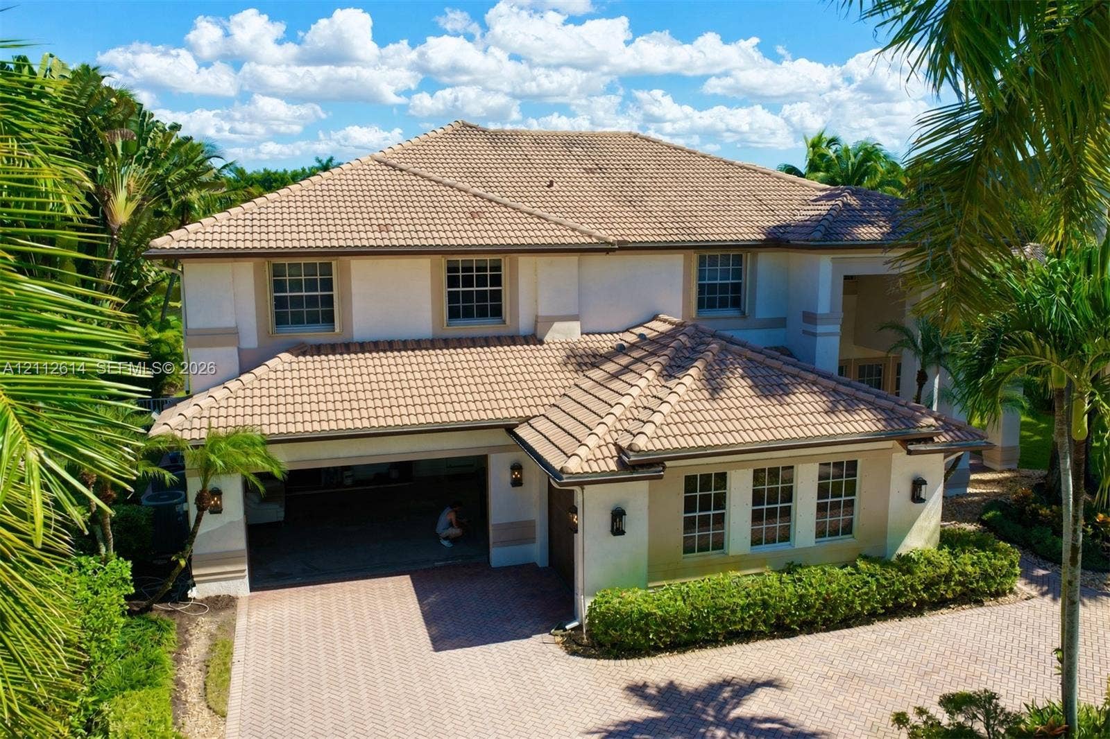 1422 Victoria Isle Drive, Weston, FL 33327 Two-story stucco exterior featuring a multi-hipped tile roof, paver driveway, multi-car garage, and grid-pattern window panes