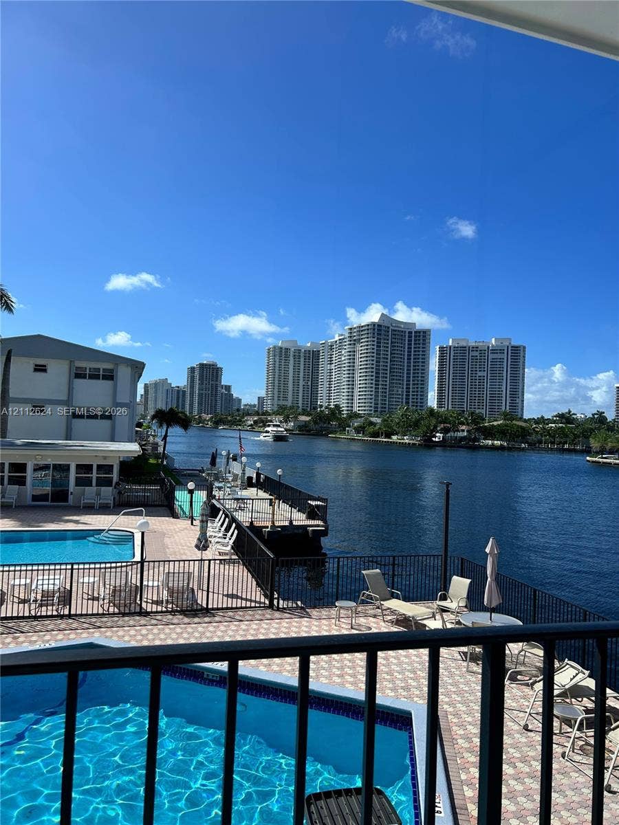 Waterfront swimming pool with paver decking, metal perimeter fencing, and deep-water canal access featuring a private dock