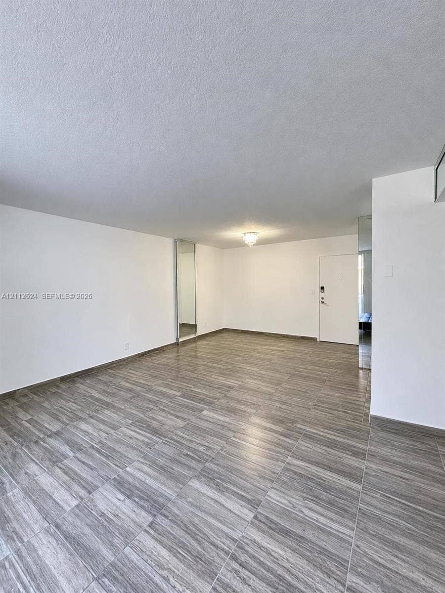 Open-concept room featuring neutral wall finishes, wood-finish tile flooring, recessed mirror panels, and a flush-mount ceiling light fixture