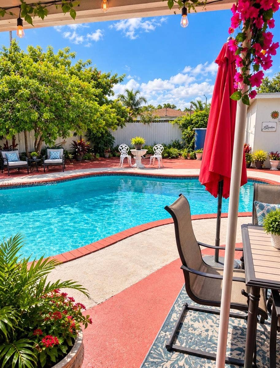 240 E 39th Street, Hialeah, FL 33013 Outdoor swimming pool with brick coping, concrete patio, mature landscaping, and perimeter fencing