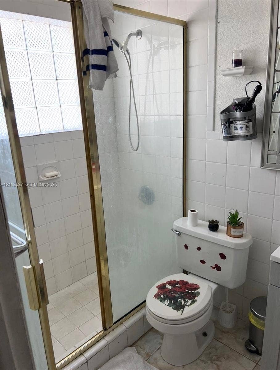 240 E 39th Street, Hialeah, FL 33013 Walk-in shower enclosure featuring gold-tone metal framing and integrated glass block window