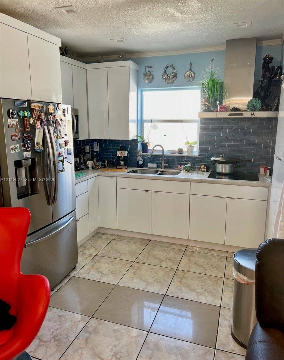 240 E 39th Street, Hialeah, FL 33013 Kitchen featuring white cabinetry, stainless steel appliances, dark subway tile backsplash, and ceramic floor tiling