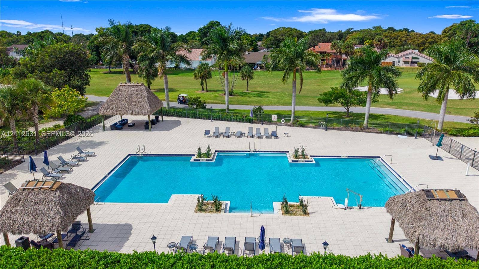 8257 NW 79th Avenue, Tamarac, FL 33321 Swimming pool featuring a tiled deck, built-in structural planters, and multiple thatched-roof pavilions