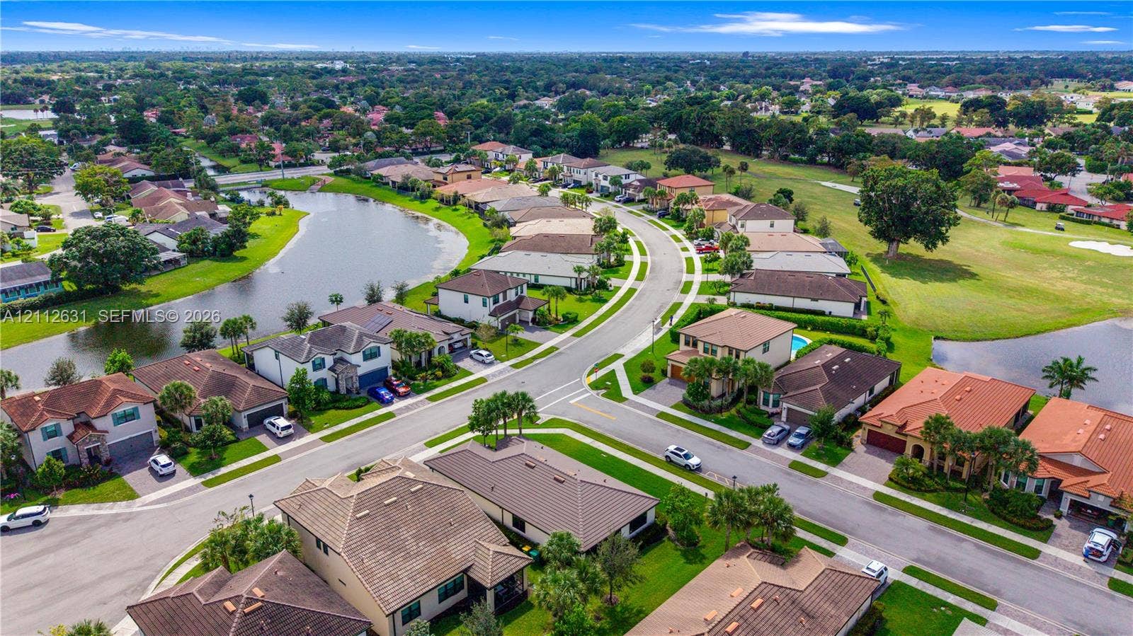 8257 NW 79th Avenue, Tamarac, FL 33321 Aerial perspective of residential neighborhood featuring a winding lake, paved streets, manicured green space, and tile-roofed homes