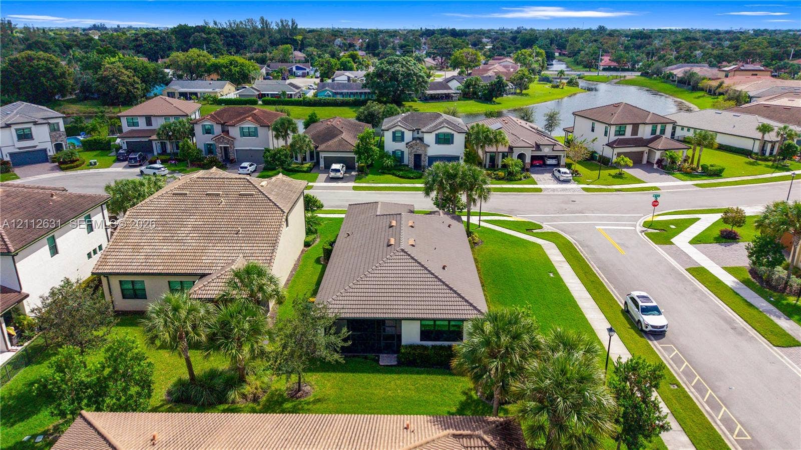 8257 NW 79th Avenue, Tamarac, FL 33321 Aerial perspective of a single-story residence featuring a hipped tile roof, concrete driveway, attached multi-car garage, and manicured landscaping
