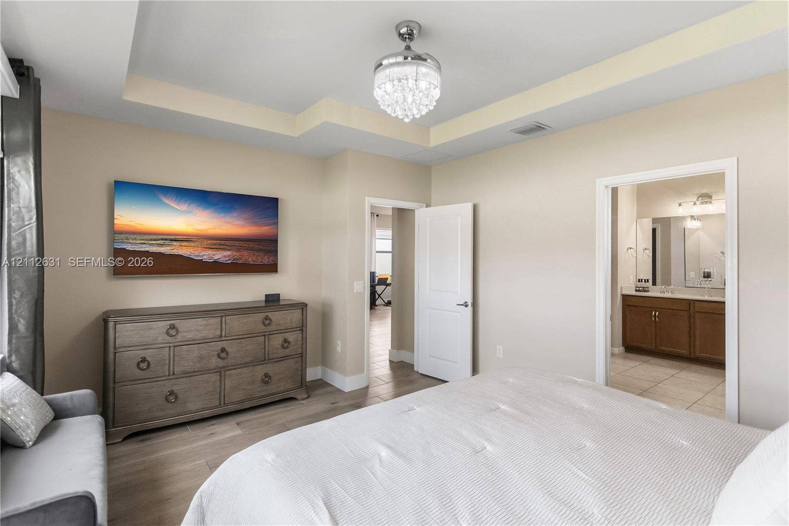 8257 NW 79th Avenue, Tamarac, FL 33321 Tray ceiling, crystal-style ceiling fan fixture, wood-finish flooring, and solid-core interior door