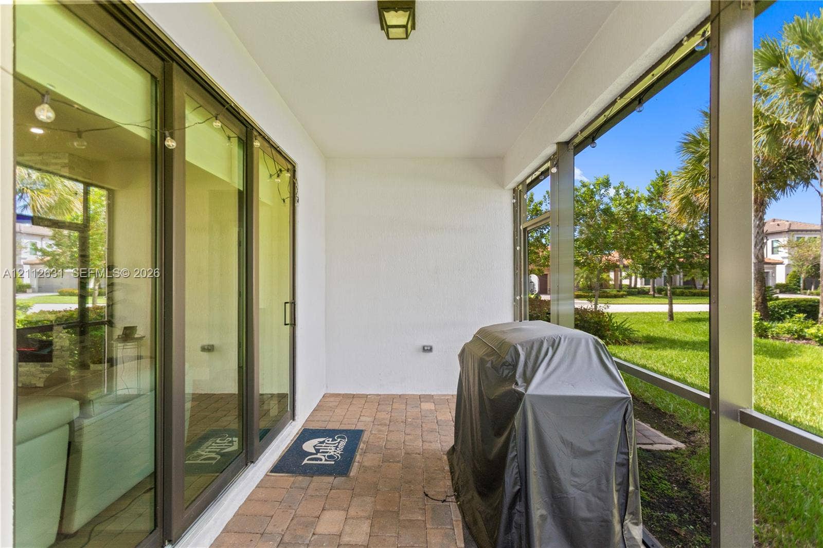 8257 NW 79th Avenue, Tamarac, FL 33321 Screened-in lanai featuring paver flooring, overhead lighting, and floor-to-ceiling glass sliding doors