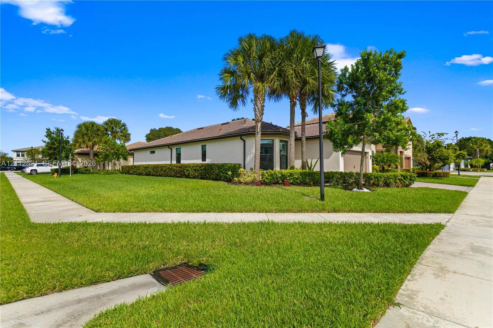 8257 NW 79th Avenue, Tamarac, FL 33321 Corner lot featuring a stucco exterior, a tiled roof, mature palm trees, and manicured hedges