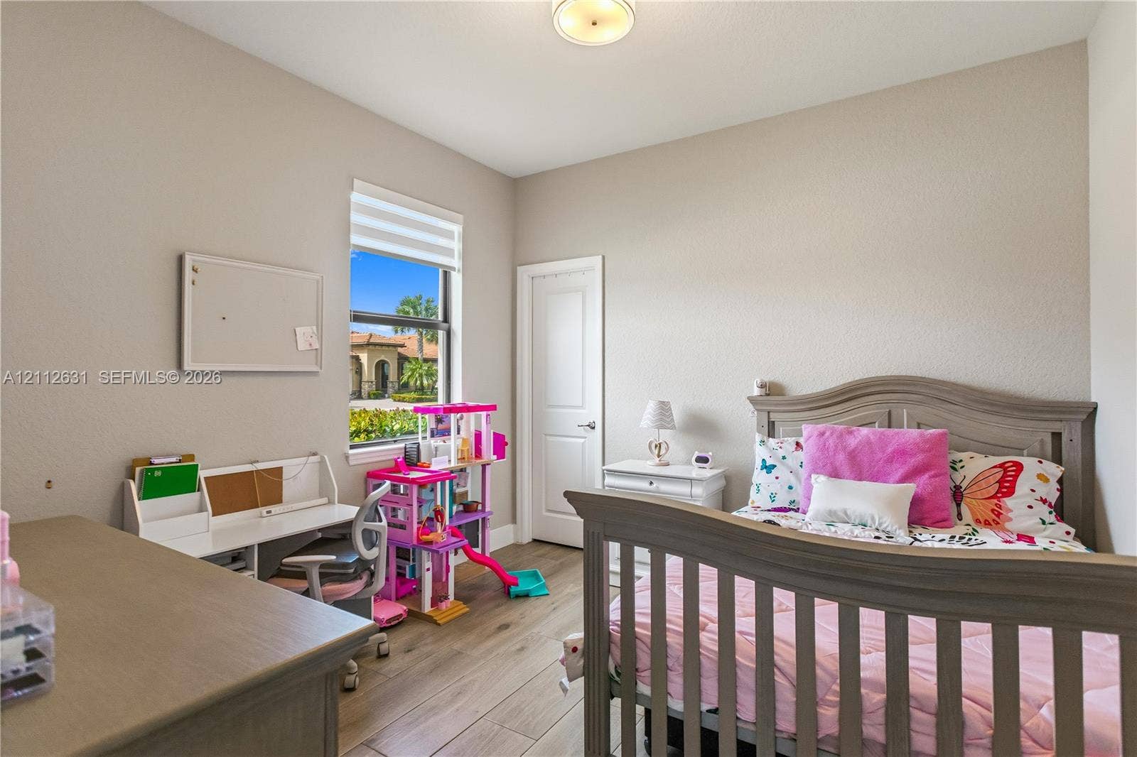 8257 NW 79th Avenue, Tamarac, FL 33321 Interior room featuring wood-finish flooring, a neutral wall palette, a single-hung window with a roller shade, and a multi-panel interior door