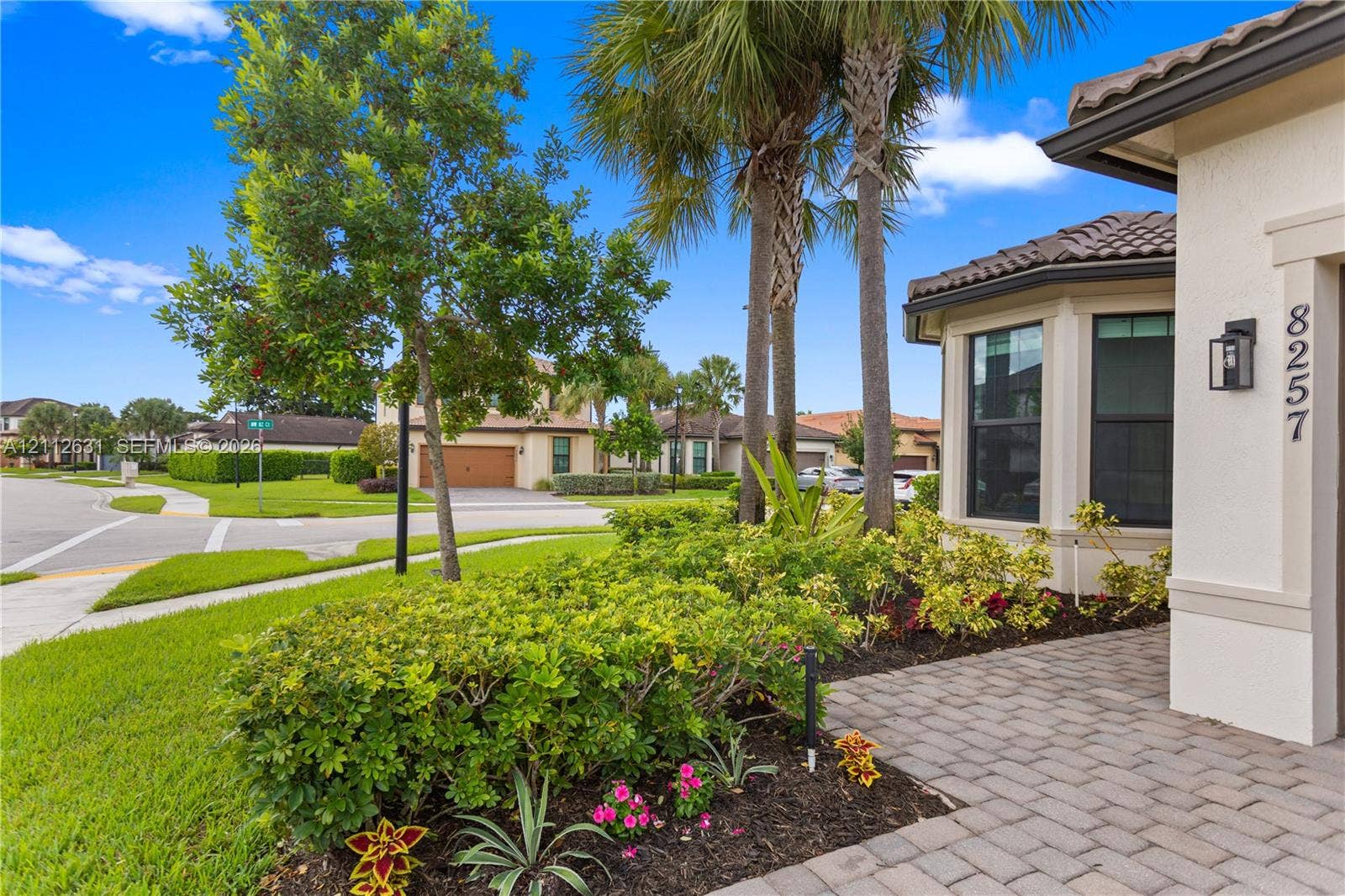 8257 NW 79th Avenue, Tamarac, FL 33321 Stucco exterior featuring a tiled roof, paved entryway, and manicured landscaping with established palm trees