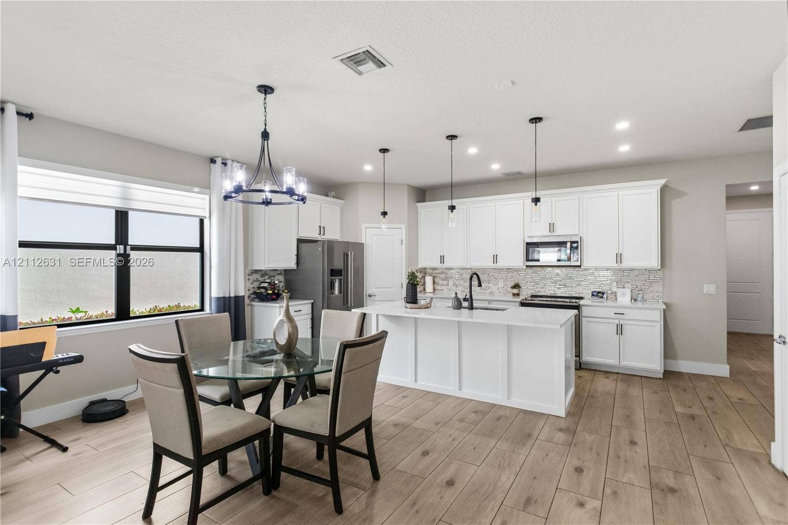 8257 NW 79th Avenue, Tamarac, FL 33321 Kitchen featuring white cabinetry, a center island with a stone-finish countertop, wood-finish flooring, a decorative chandelier, and recessed lighting