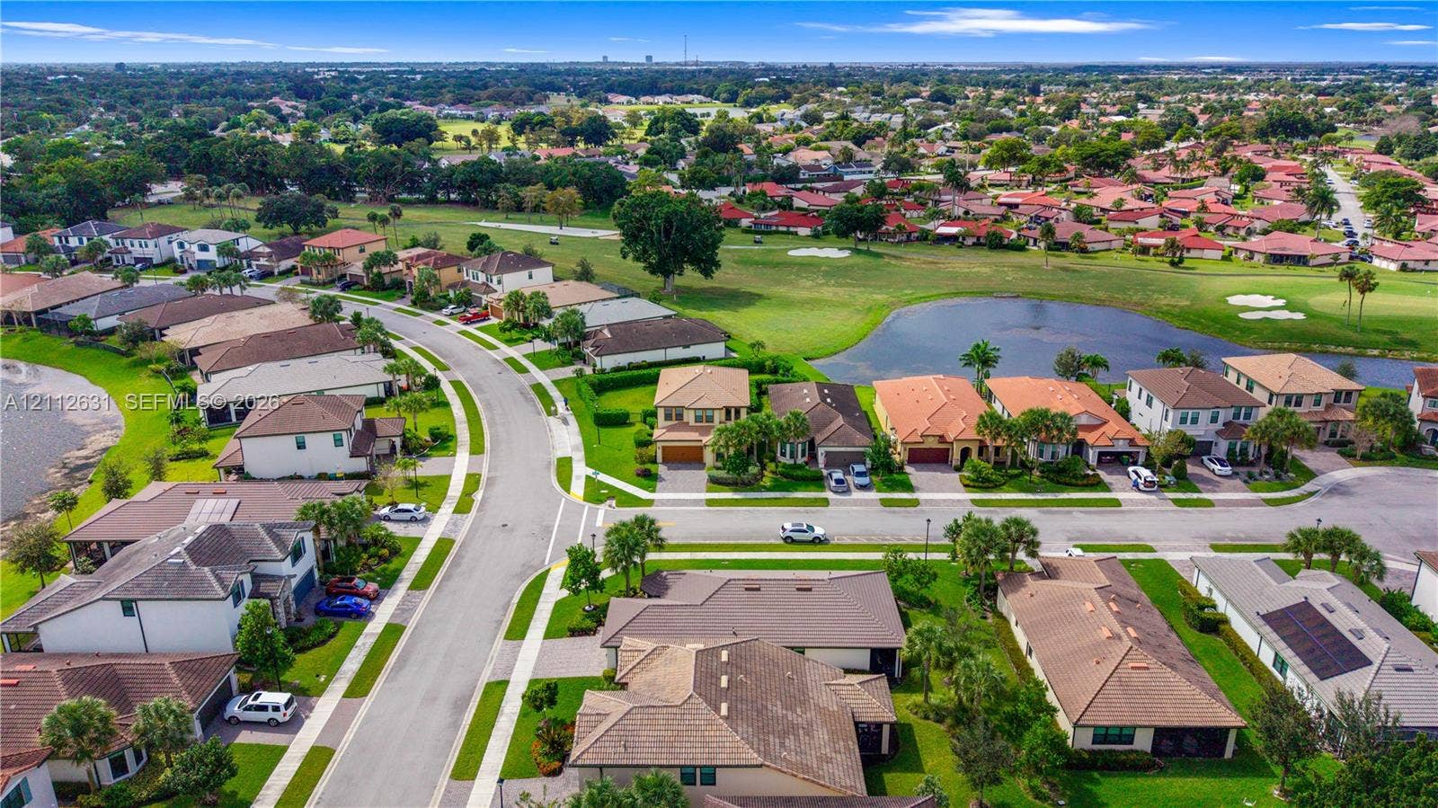 8257 NW 79th Avenue, Tamarac, FL 33321 Aerial perspective featuring multi-story residential structures, paved street infrastructure, landscaped green spaces, and a neighborhood water feature