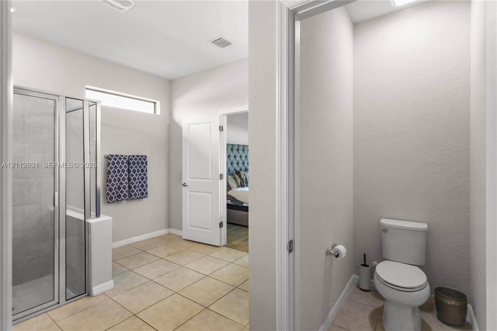 8257 NW 79th Avenue, Tamarac, FL 33321 Shower enclosure with framed glass door, tile flooring, high-set horizontal window, and enclosed water closet