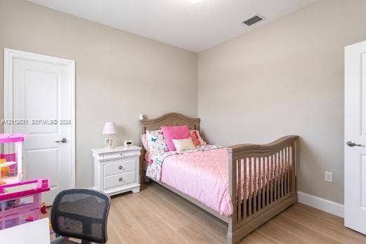 8257 NW 79th Avenue, Tamarac, FL 33321 Neutral-toned interior space featuring wood-finish flooring, two white paneled doors, and a ceiling-mounted light fixture