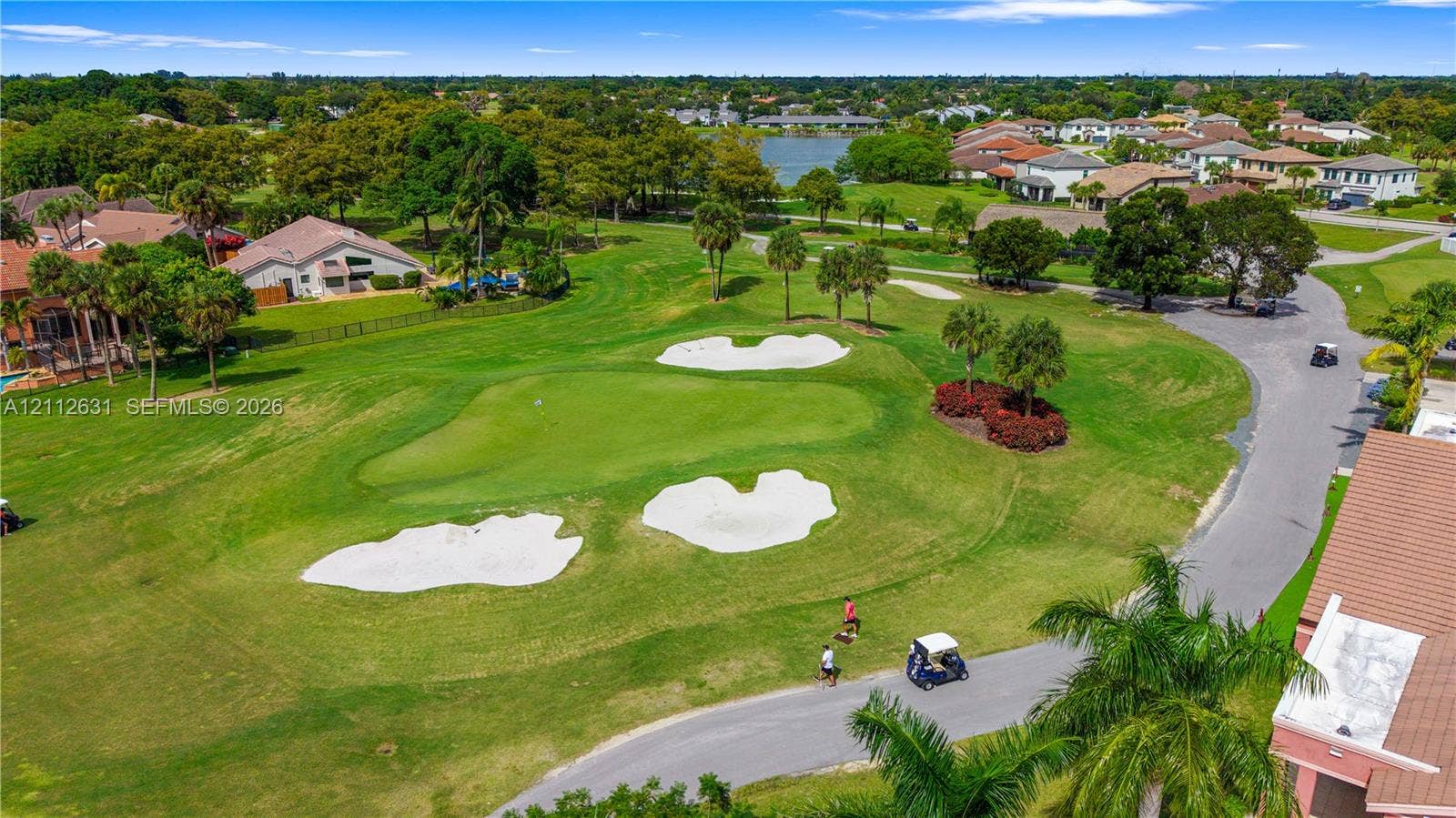 8257 NW 79th Avenue, Tamarac, FL 33321 Aerial perspective of a golf course featuring manicured putting greens, sand bunkers, mature palm trees, and water frontage