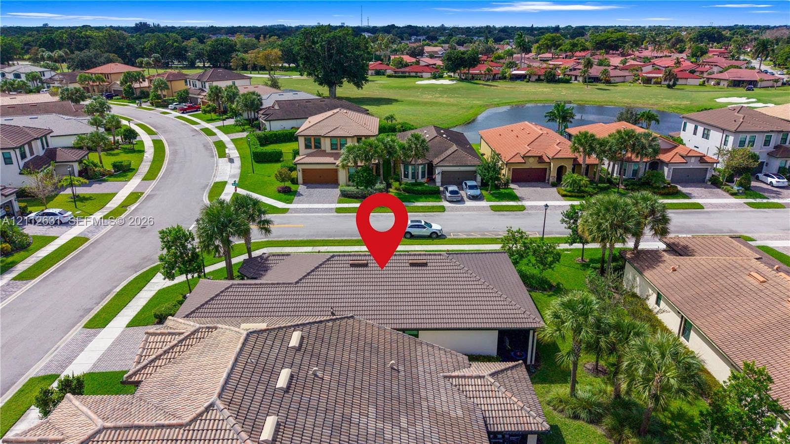 8257 NW 79th Avenue, Tamarac, FL 33321 Aerial perspective featuring a multi-gabled tiled roof structure with integrated skylights, positioned within a landscaped residential community featuring expansive manicured lawns and mature palm trees