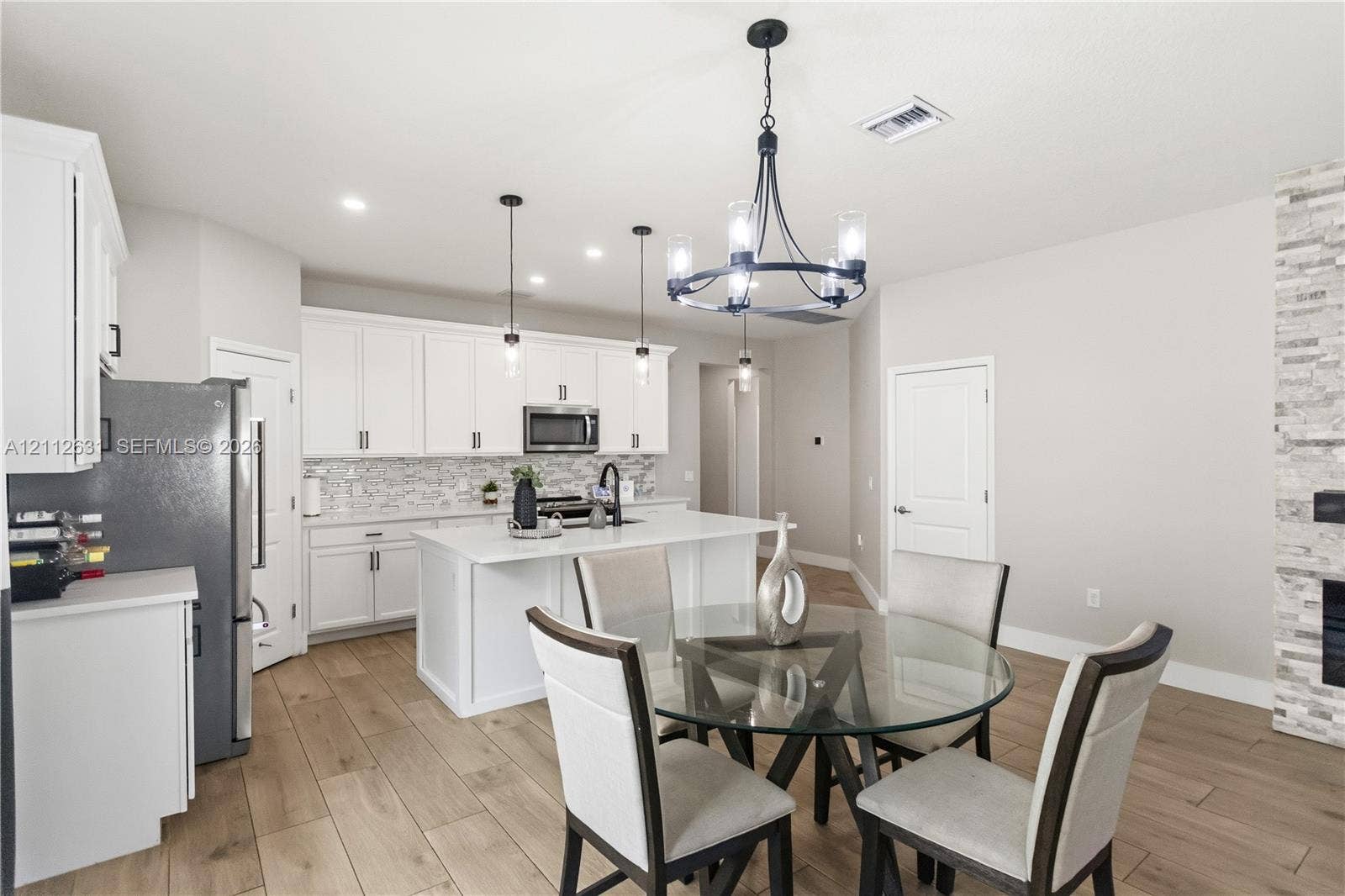8257 NW 79th Avenue, Tamarac, FL 33321 Kitchen featuring white cabinetry, quartz countertops, a central island, wood-finish flooring, and a stone-clad fireplace