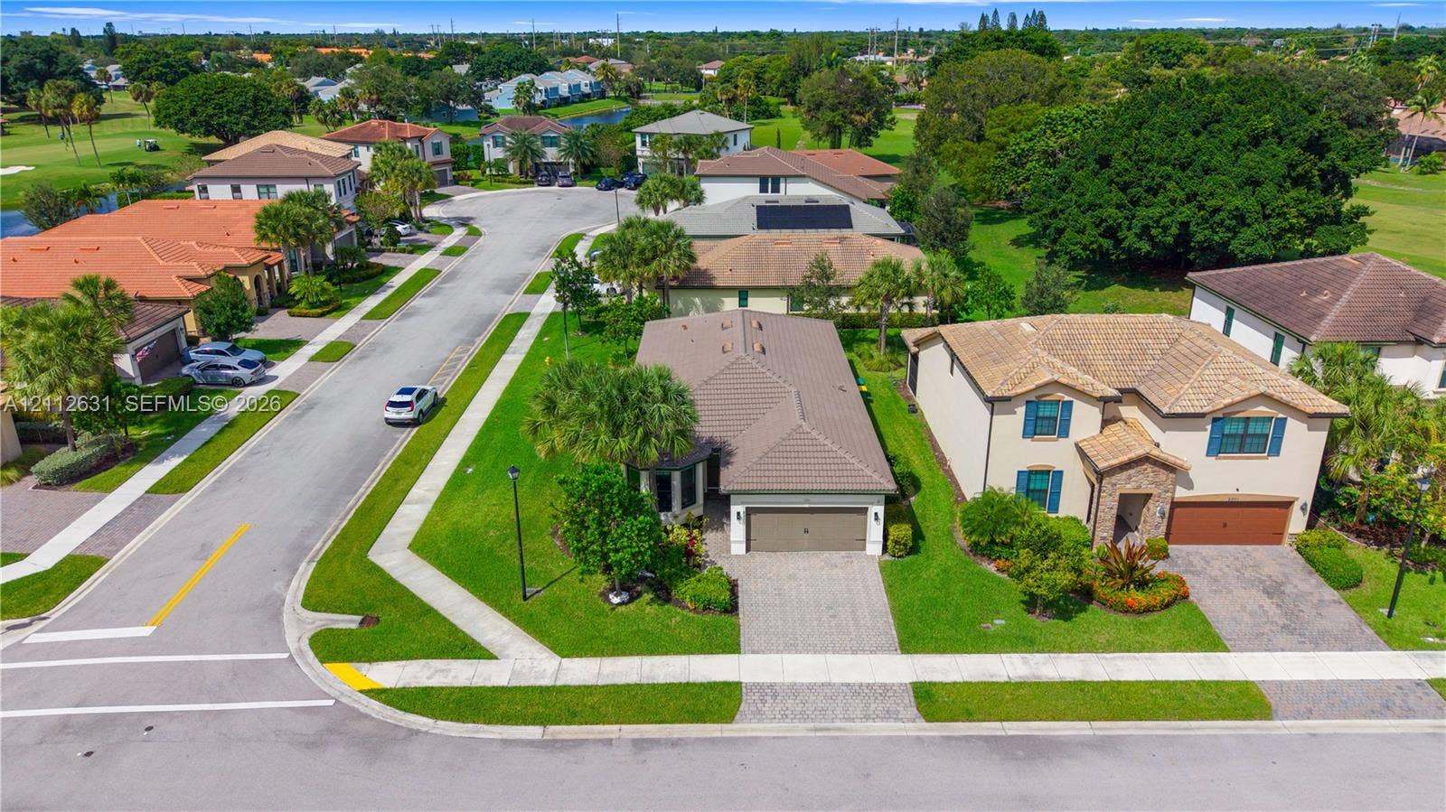 8257 NW 79th Avenue, Tamarac, FL 33321 Aerial perspective featuring concrete tile roof systems, paver driveways, manicured green space, and mature landscape plantings