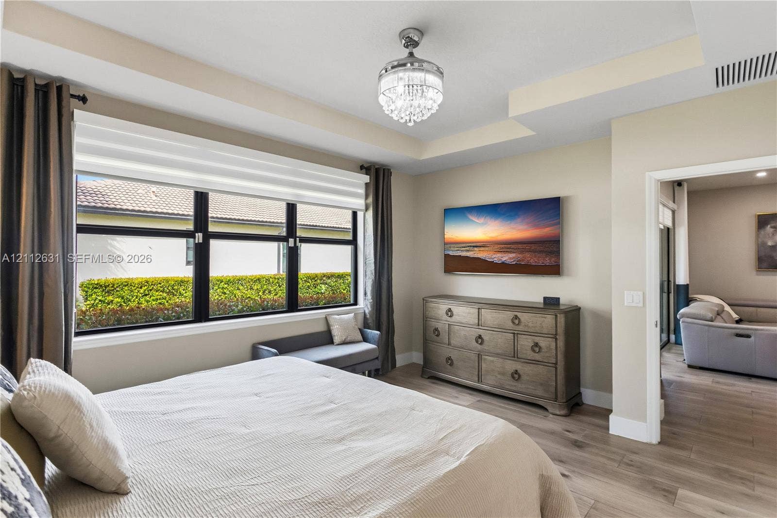 8257 NW 79th Avenue, Tamarac, FL 33321 Tray ceiling featuring a crystal chandelier, wood-finish flooring, and large windows with black frames